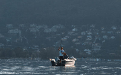 Homme pêchant sur un lac depuis son bateau
